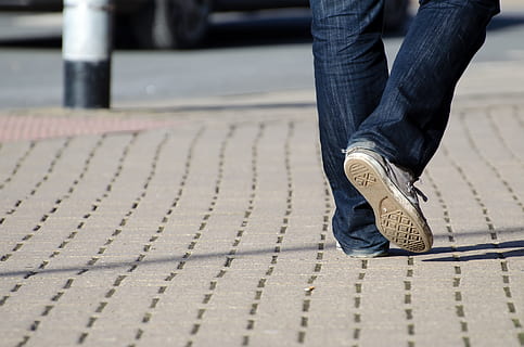 person in blue jeans with white sneakers walking on concrete road HD wallpaper