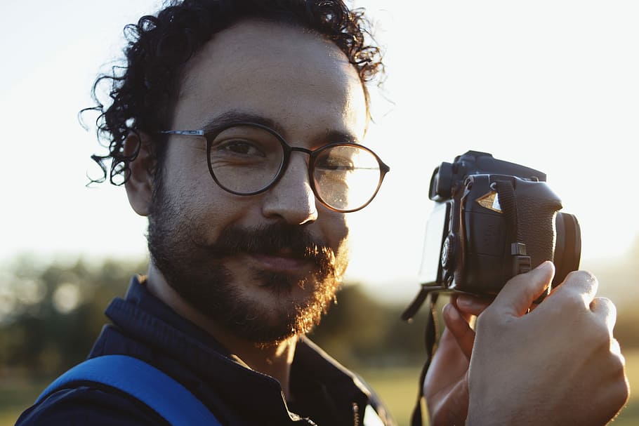 man wearing eyeglasses holding DSLR camera, curly, curly hair HD wallpaper
