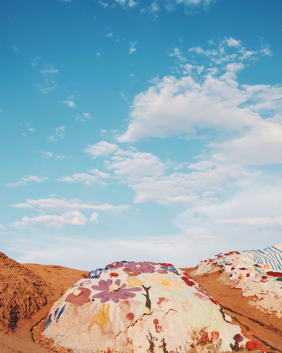 hill under white clouds during daytime, pink and white floral printed rock HD wallpaper