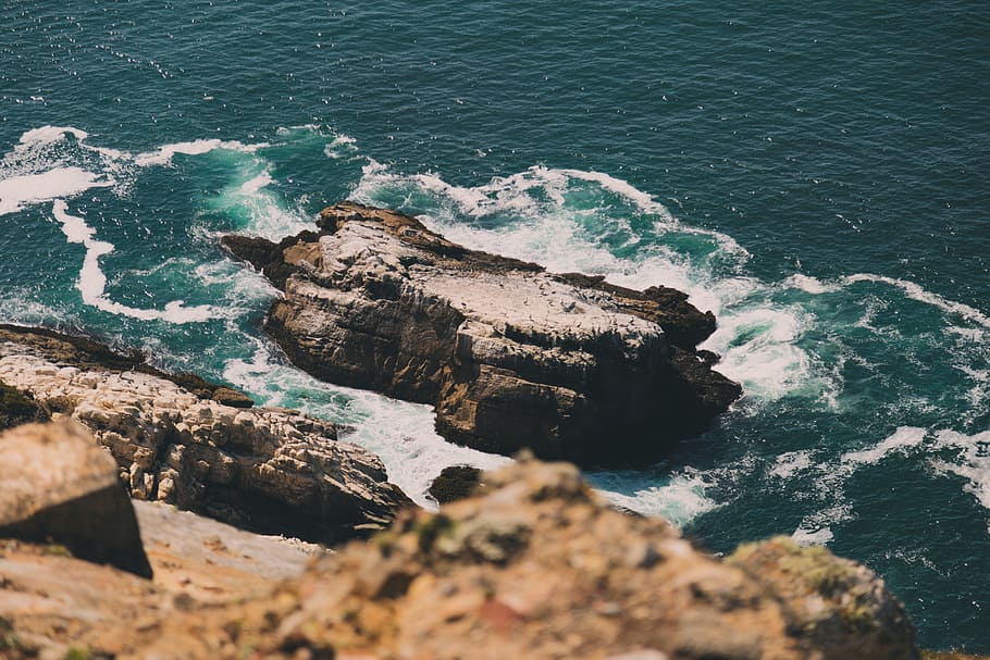 rock formation on body of water during daytime, high-angle photography of rock on body of water HD wallpaper