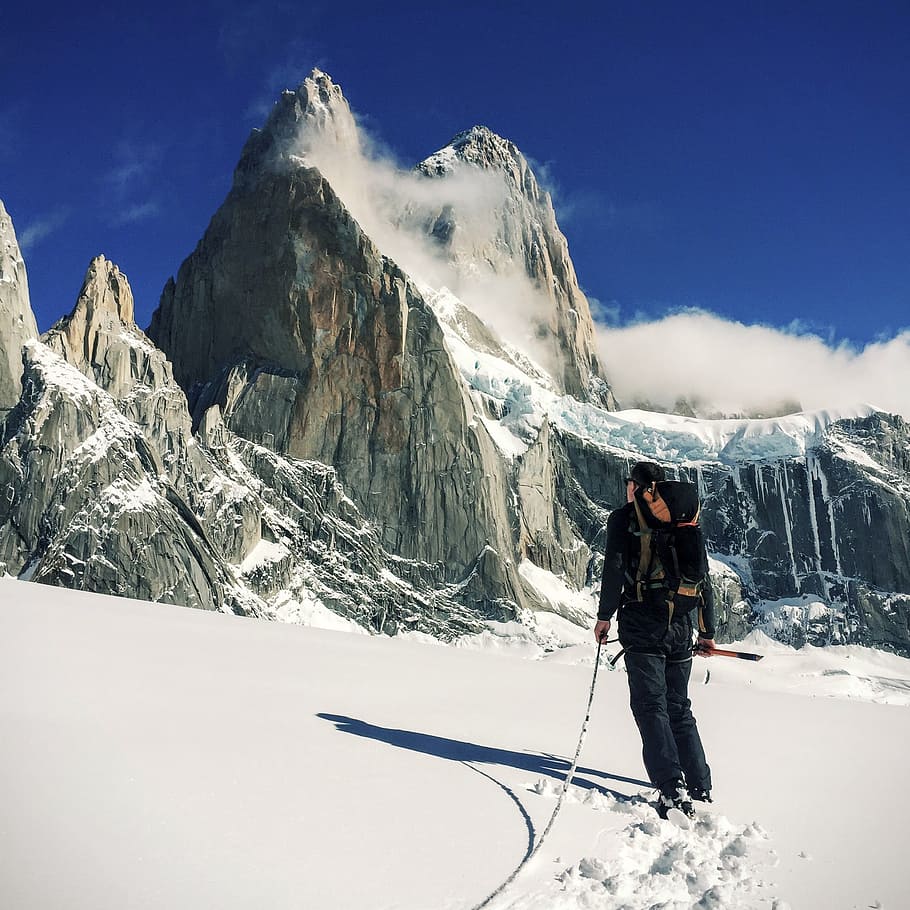 person walking on snow field near mountain, man climbing on the mountain covered snow HD wallpaper