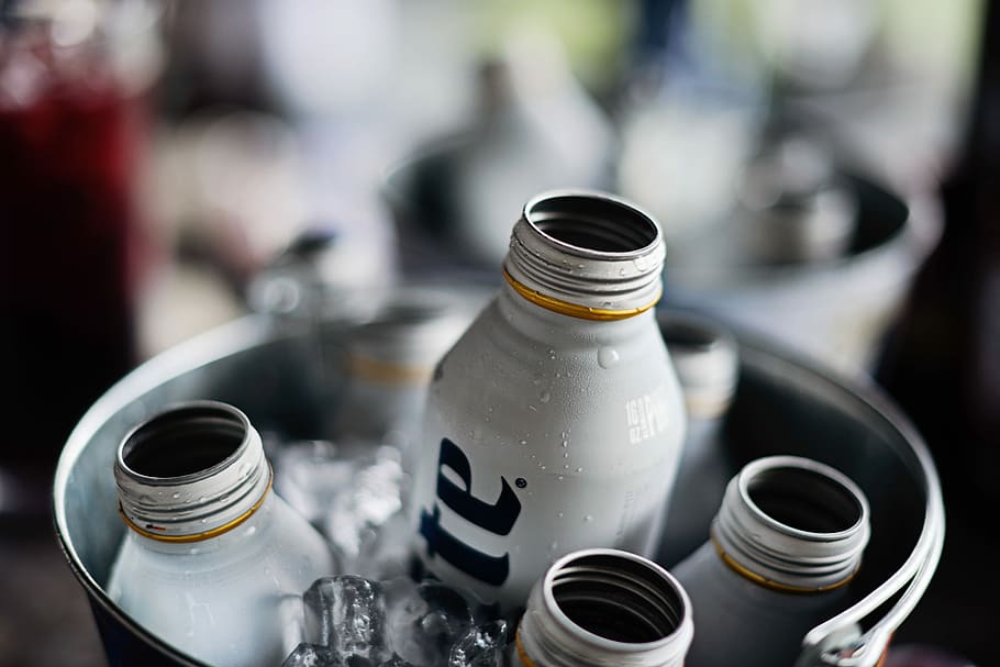 shallow focus photography of liquor bottles inside a bucket filled with ice, selective focus photography of product bottles on bucket with ice