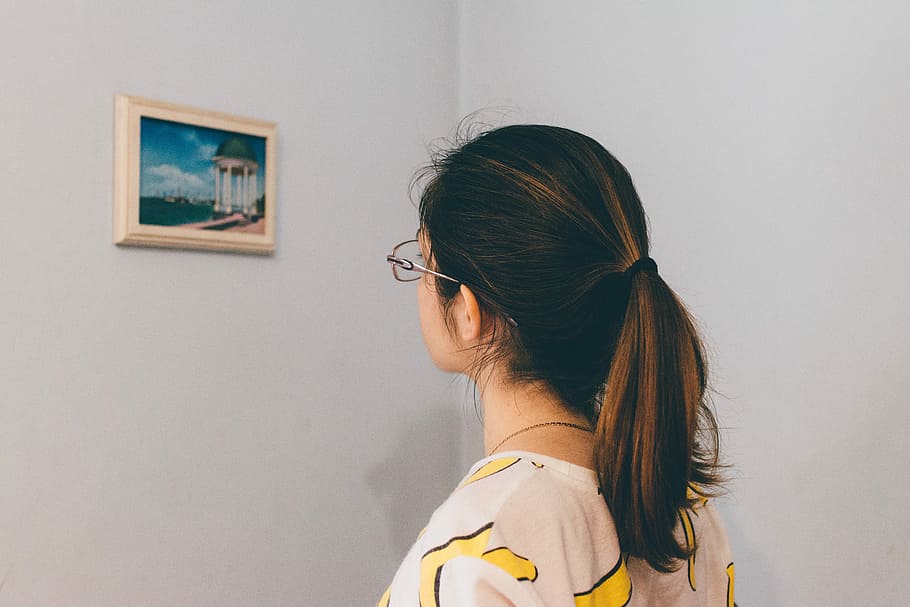 woman in eyeglasses standing and staring at the painting on the wall HD wallpaper