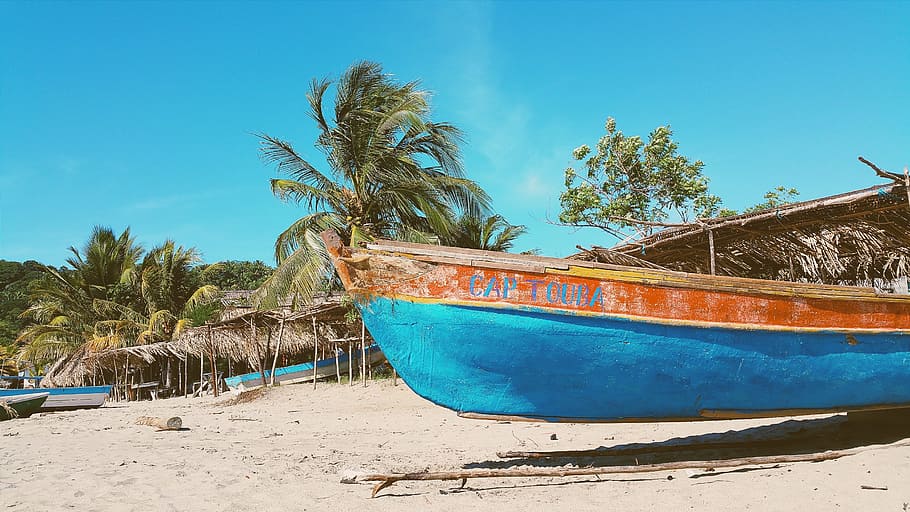 brown and blue wooden canoe on sand under blue sky during daytime HD wallpaper