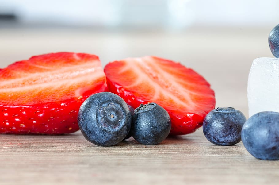 selective focus photography of strawberry and blueberries, selective focus photography of cut strawberries and four blueberries HD wallpaper