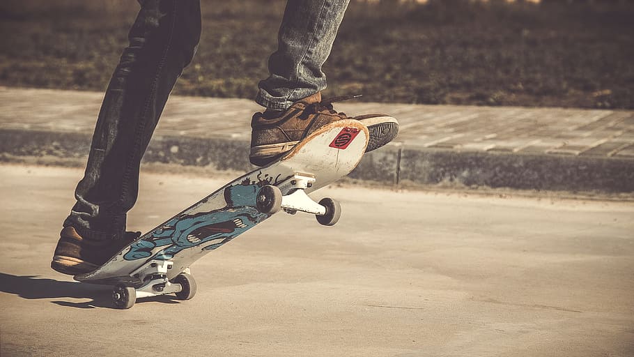 person riding skateboard during daytime, person wearing jeans playing skateboard