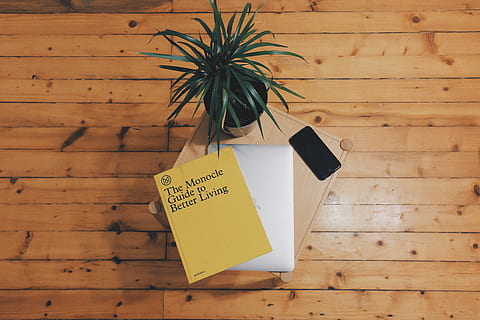 The Monocle Guide To Better Living book on top of laptop beside plant HD wallpaper