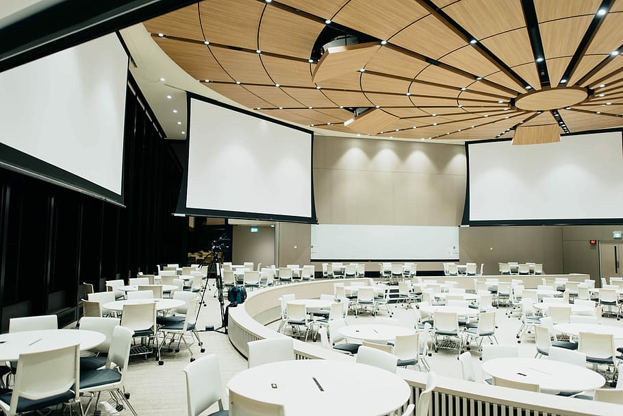 photo of empty room with projector screen, table setup in a well-lit auditorium HD wallpaper