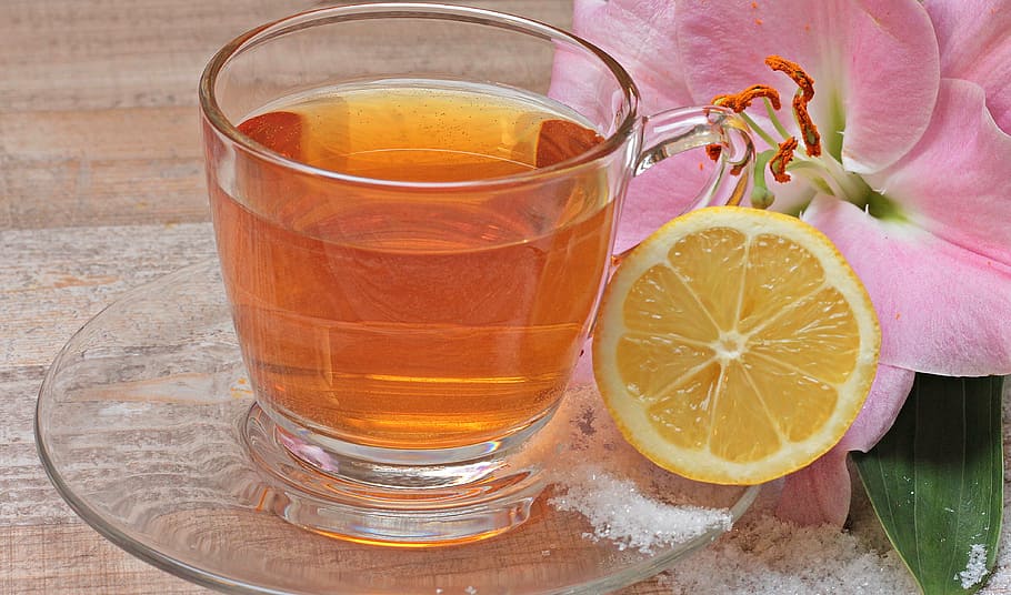 clear glass mug filled with orange liquid, tee, lemon, flower