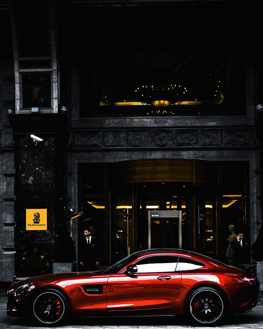 red coupe parked in front of black and gray building during daytime, red Mercedes-Benz AMG GT parked near black concrete building with glass door