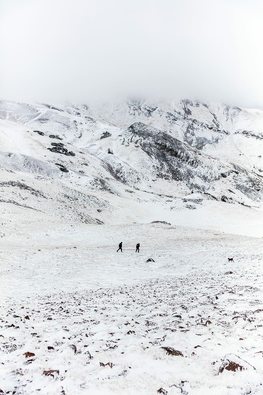 two people walking on snow, two person walking along snow covered hill HD wallpaper
