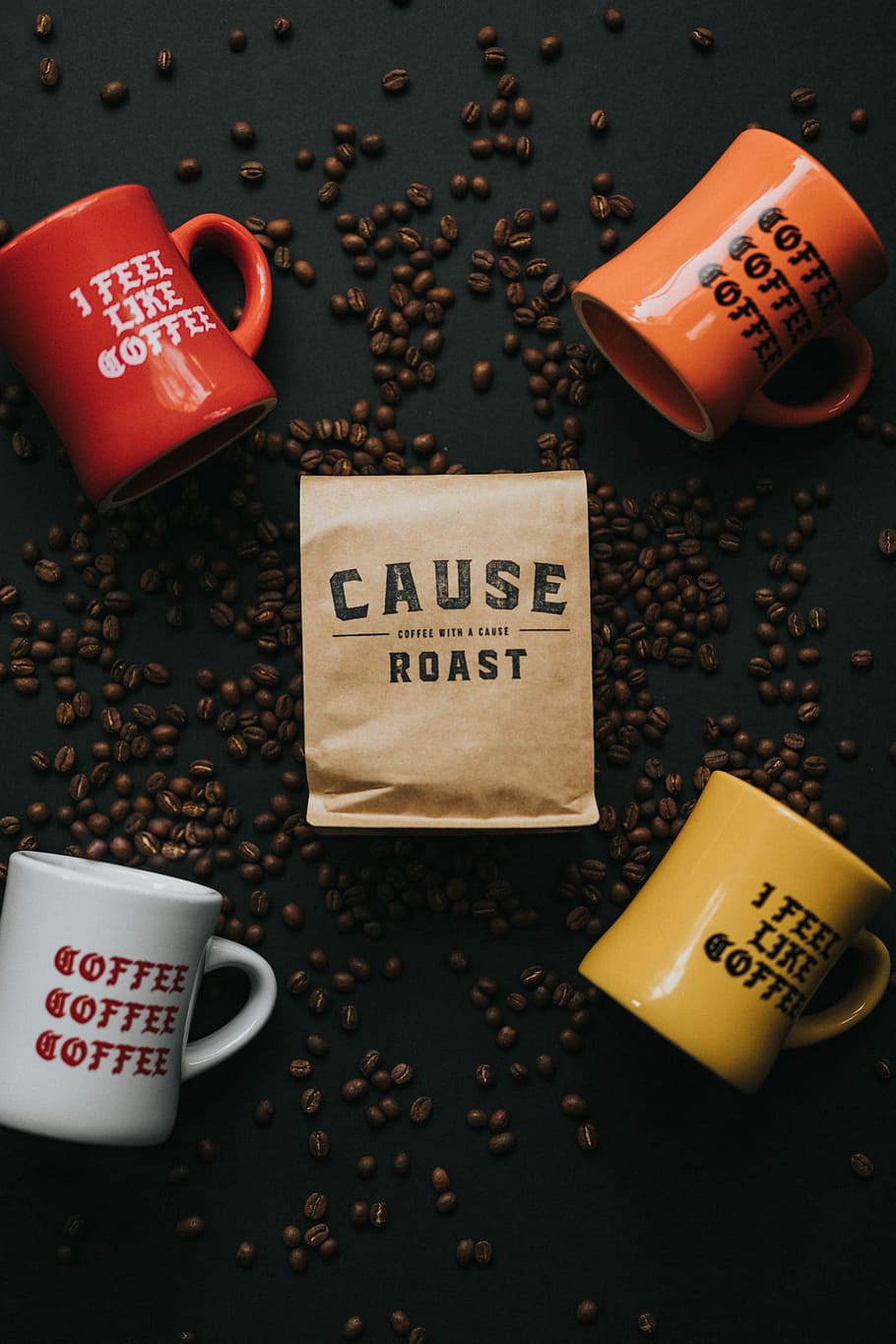 four assorted-color cups, four assorted-color ceramic mugs on black surface with coffee beans HD wallpaper