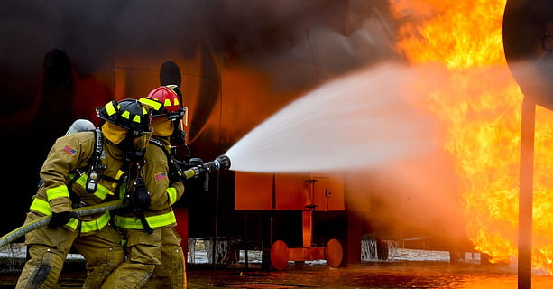 two fireman holding fire hose with water splashes on flame HD wallpaper