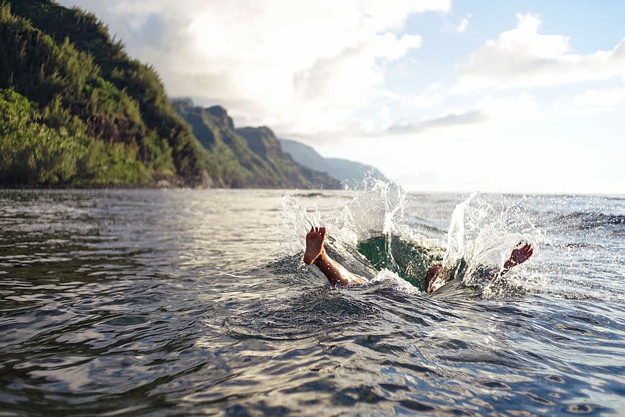person on water under gray sky, person swimming in water near mountain during daytime HD wallpaper