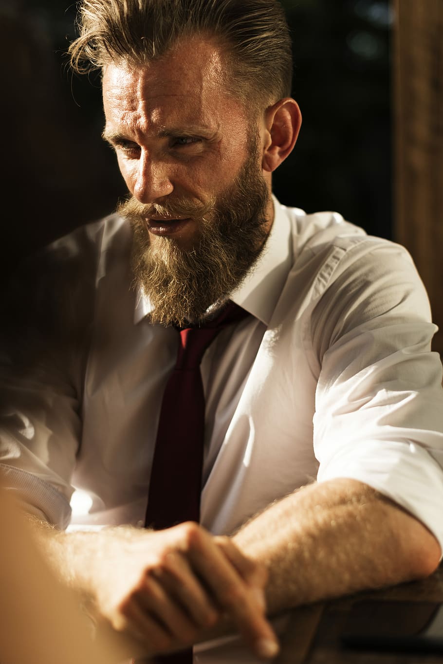 Elegant bearded man at a table, man wearing white long-sleeved taking selfie