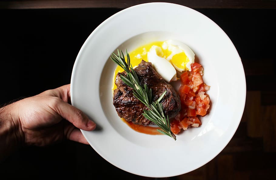 person showing beef with egg and tomato on white ceramic plate HD wallpaper