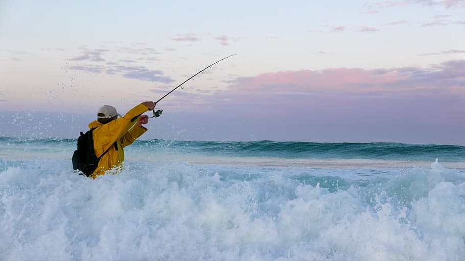 man wearing orange windbreaker jacket holding telescopic fishing rod on sea water, HD wallpaper