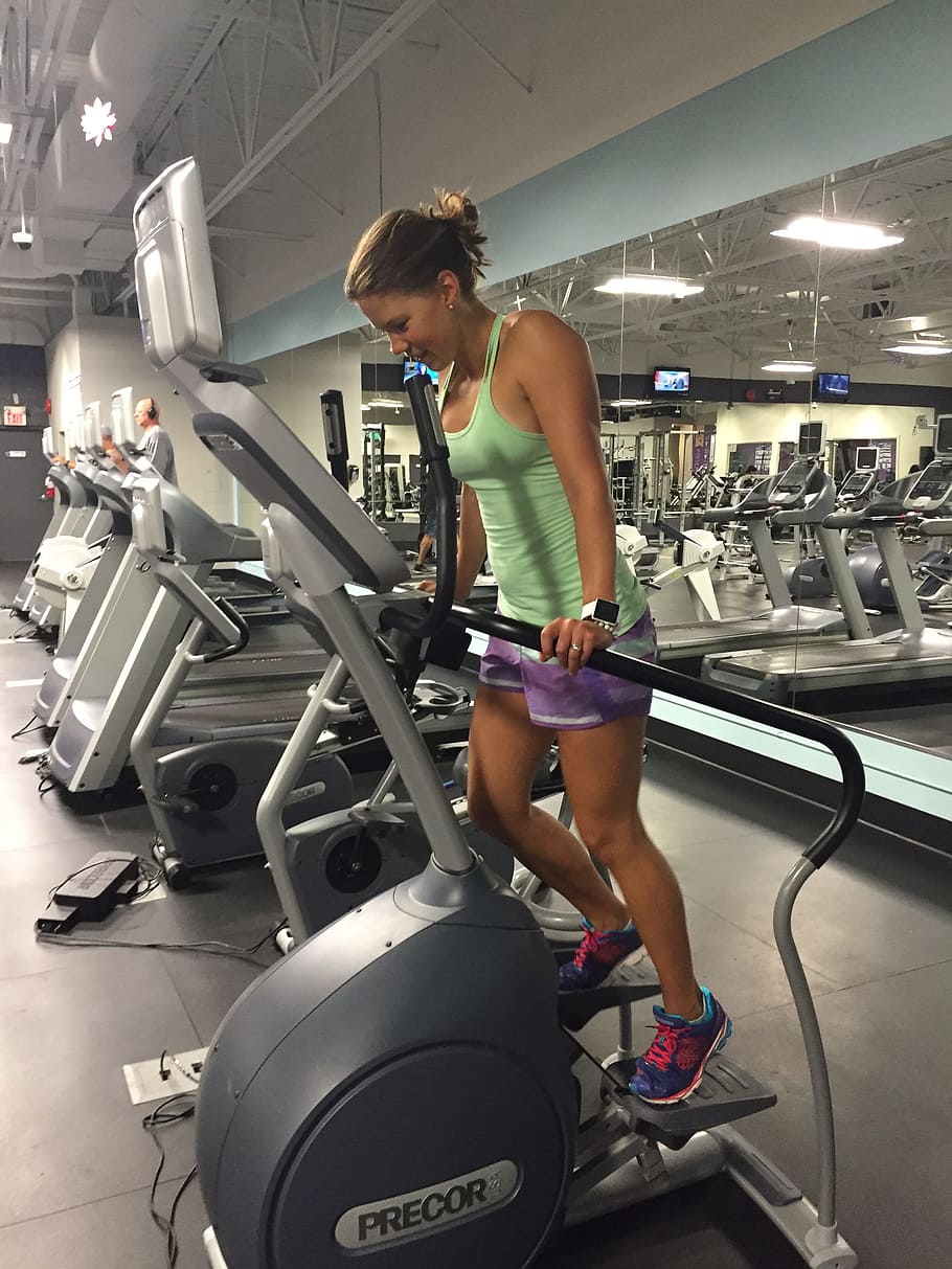 woman in green tank top using Precor exercise equipment, fitness