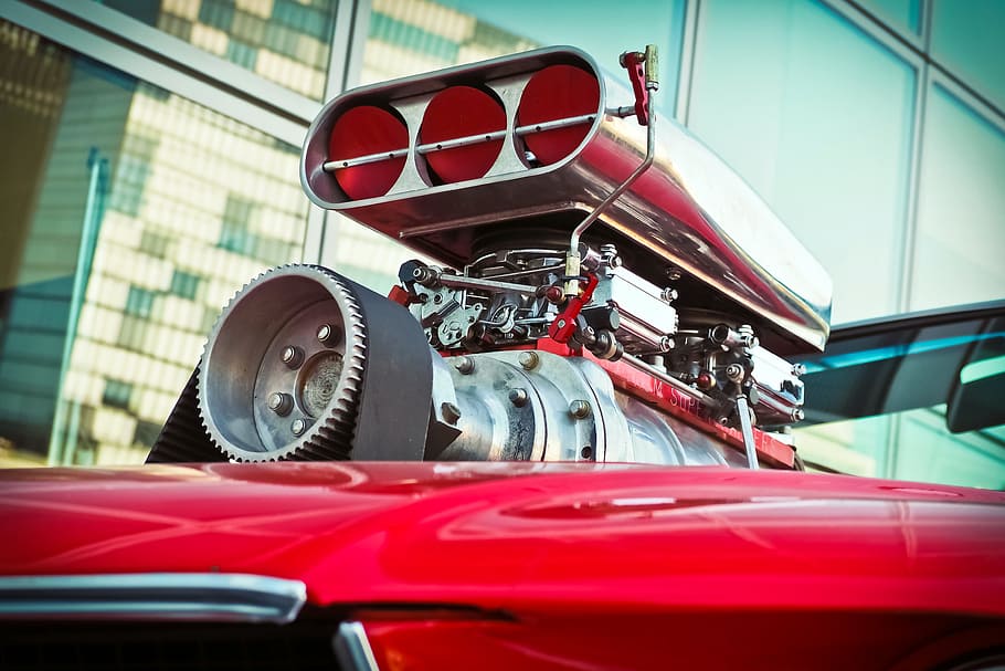 close-up photo of red vehicle with supercharger and intake manifold