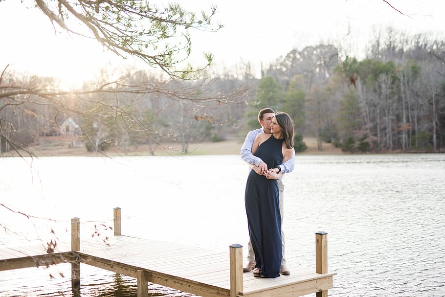 man and woman hugging on brown wooden dock during daytime, man hugging woman while standing on dock HD wallpaper