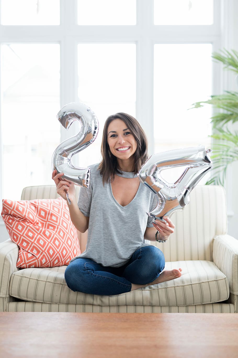 woman holding silver number balloons, woman holding silver-colored 24 inflatable balloons