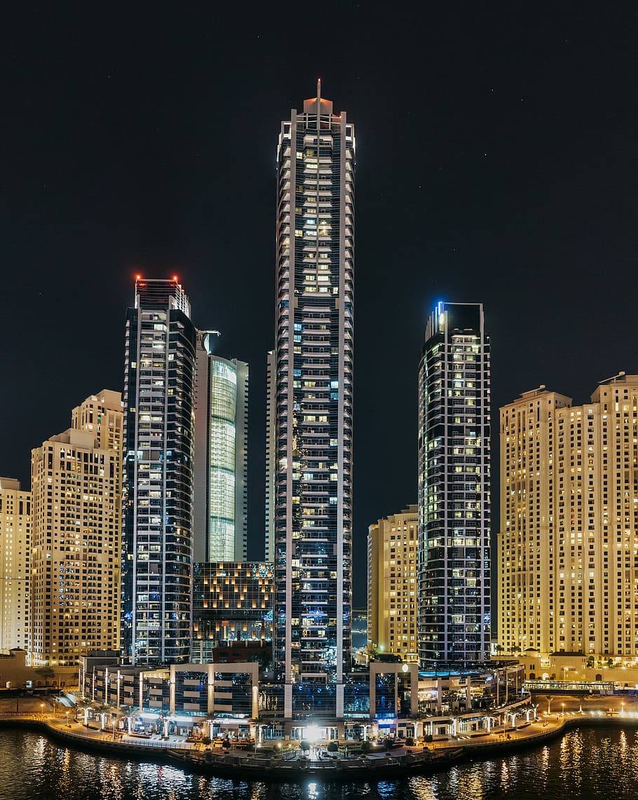 three lighted high-rise buildings near body of water, city light buildings during night time