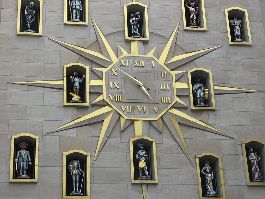 yellow and gray analog building clock with surrounded of statues HD wallpaper
