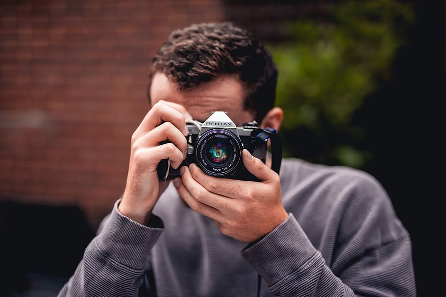 person taking photo using Pentax DSLR camera, selective focus photography of man in blue sweater taking photo HD wallpaper