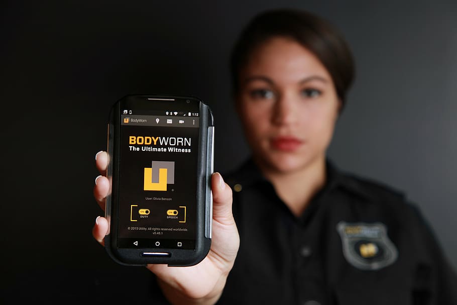 woman holding smartphone displaying bodyworn, body camera, police body camera