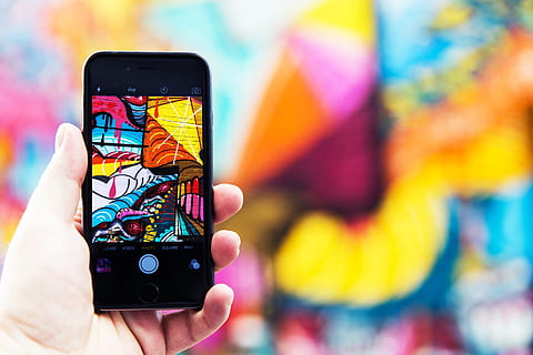 Man photographer capturing street art photo with his hand on iPhone mobile smartphone HD wallpaper
