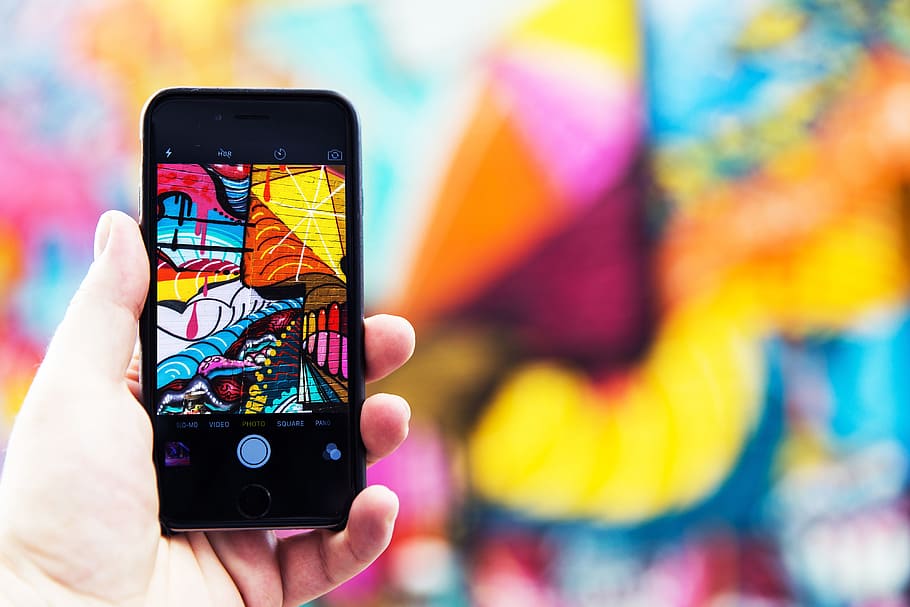 Man photographer capturing street art photo with his hand on iPhone mobile smartphone HD wallpaper