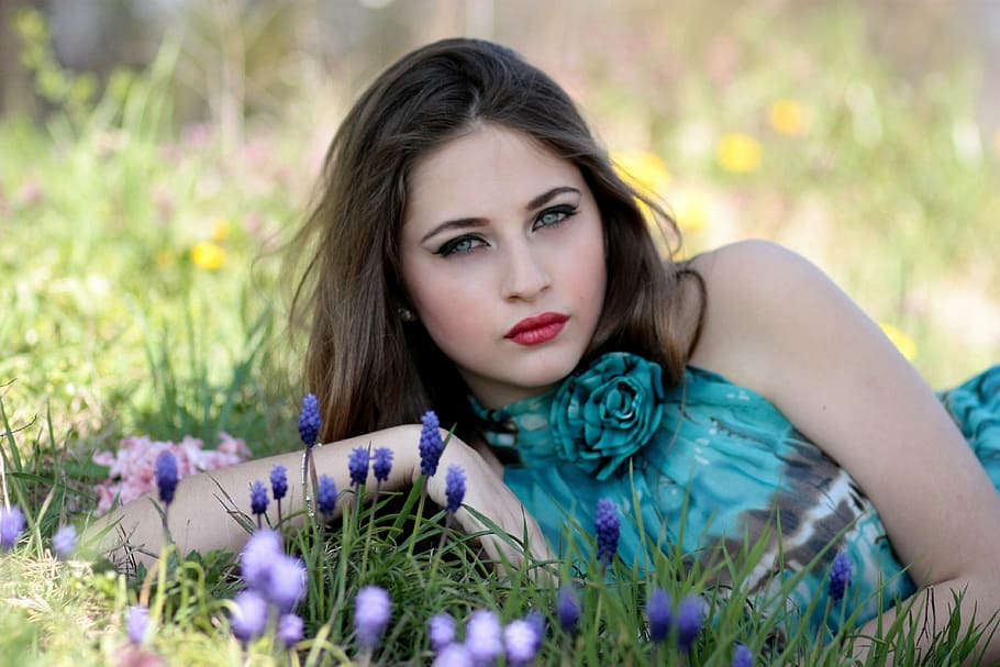 woman wearing teal and gray halter-top lying on purple flower field during daytime