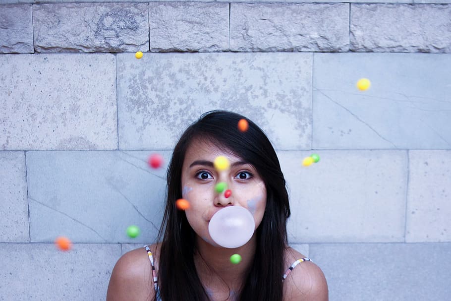 time lapse photo of woman making gum bubble, woman with bubble gum balloon near wall