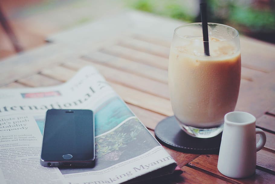 photography of space gray iPhone 5S on top of newspaper near drinking glass HD wallpaper