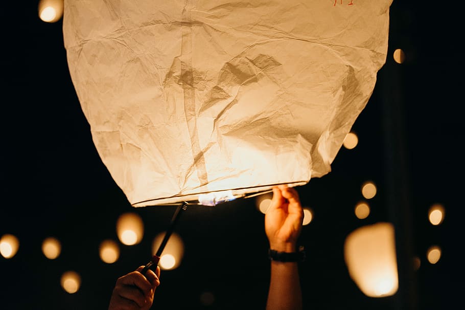 white paper lantern flying at nighttime, person holding sky lantern HD wallpaper