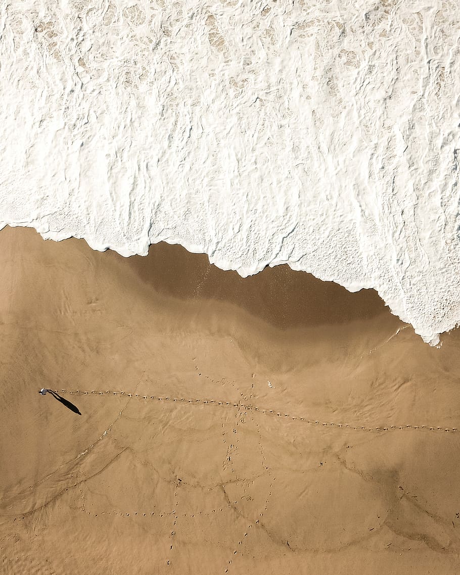 aerial view of person near beach, silver-colored chain necklace on brown surface