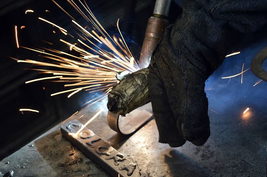 person in black gloves cutting metal using acetylene, metallurgy