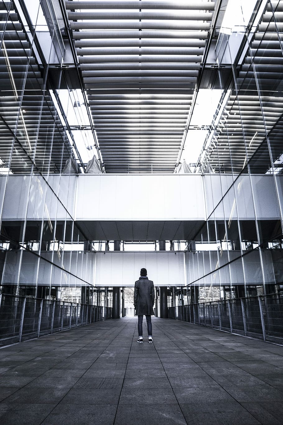 person standing near curtain wall building grayscale photography, man in black coat standing inside room HD wallpaper