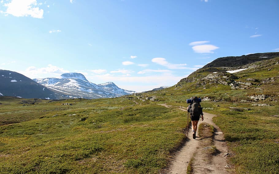 On the way to SingI, person with black hiking back walking on green field near mountains during daytime HD wallpaper
