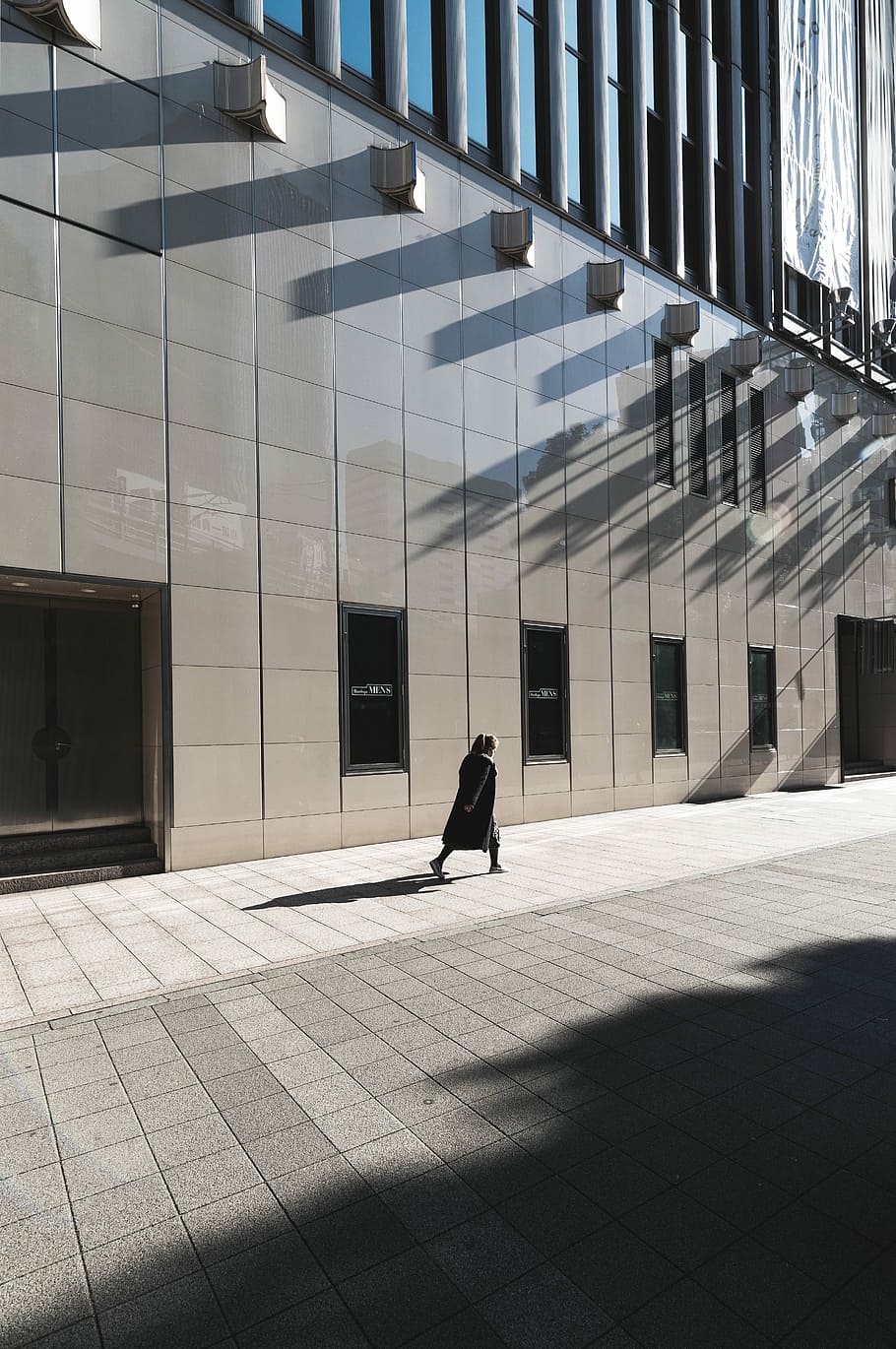 woman in black long-sleeved dress walking beside building, person walking near high-rise building during daytime HD wallpaper