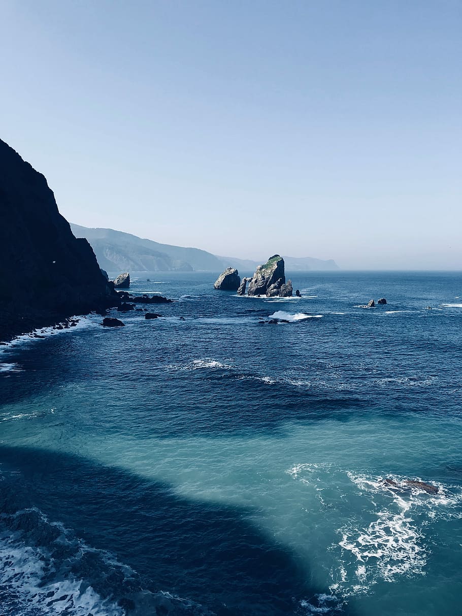 body of water near cliff, rock formation in body of water during cloudy sky HD wallpaper