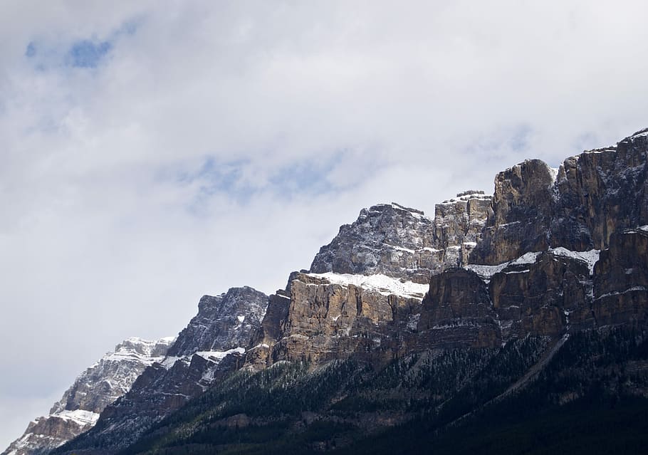 brown mountain under gray sky during daytime, low angle photography of brown cliffs HD wallpaper