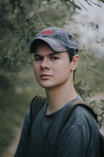 Man in a baseball hat and backpack making eye contact outsite, man wearing blue denim cadet cap HD wallpaper