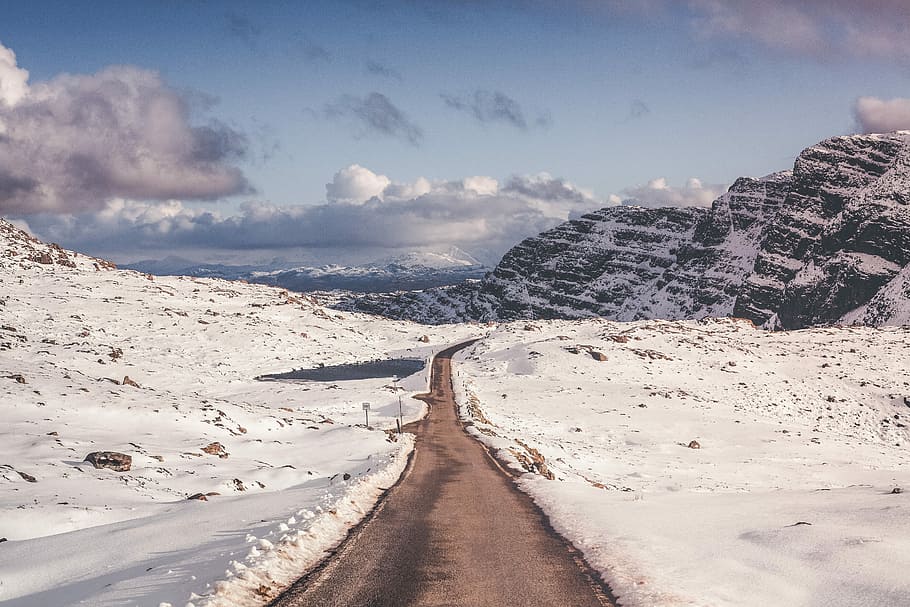 road surrounded by snow, snow covered field and mountains under blue sky HD wallpaper