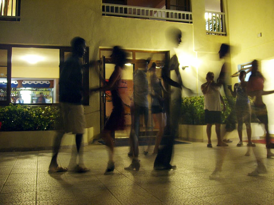 people walking and standing in front of brown concrete building during nighttime HD wallpaper