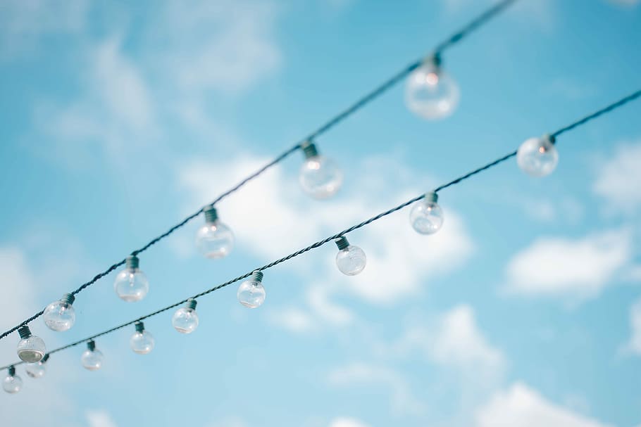 tilt lens photography of string lights under cloudy skies, selective focus photography of light bulbs HD wallpaper
