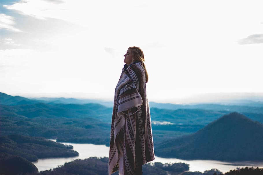 women's wearing brown and white blanket standing on top of the mountain HD wallpaper