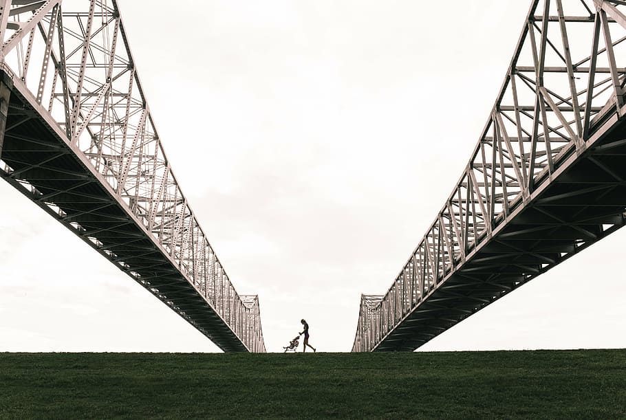 silhouette photography of person pushing stroller under bridge