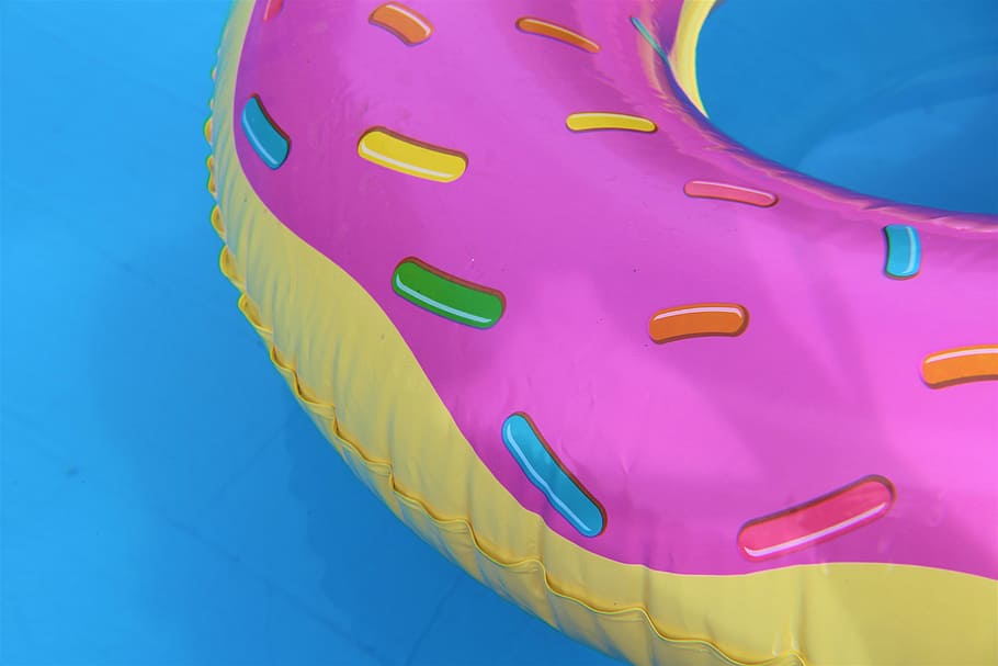 multicolored swimming pool floaters, pink and yellow inflatable on body of water HD wallpaper