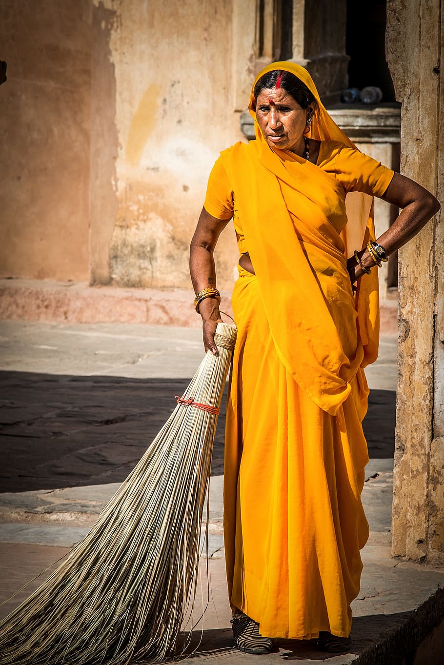 woman in yellow sari dress holding broomstick, indian woman, person